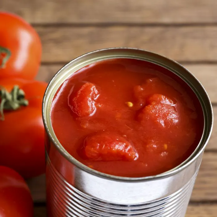 Fresh canned tomatoes in a glass jar on a wooden table.