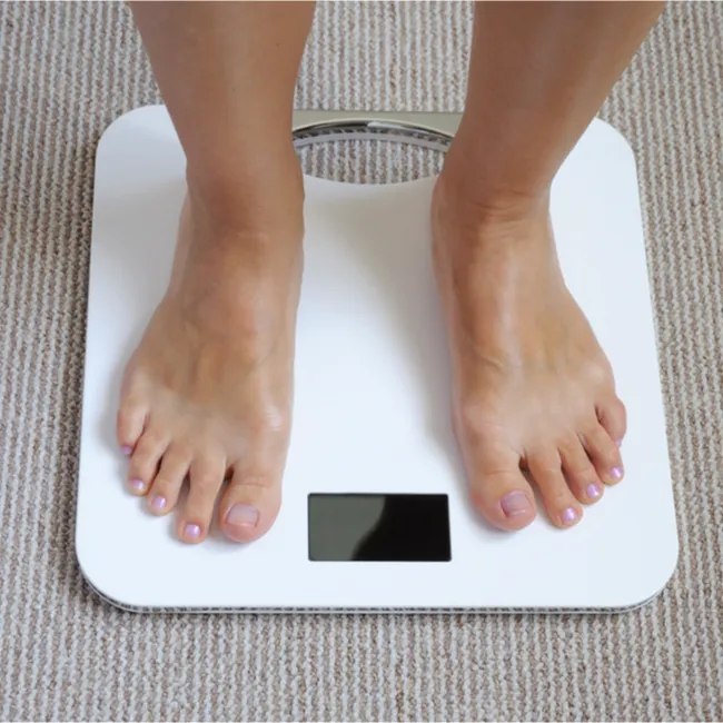 "Woman smiling while looking at a scale"