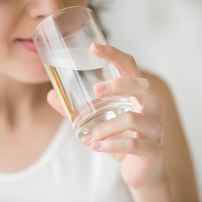 woman sipping on clear glass of water