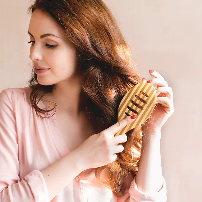 Woman with red hair brushing her hair elegantly.