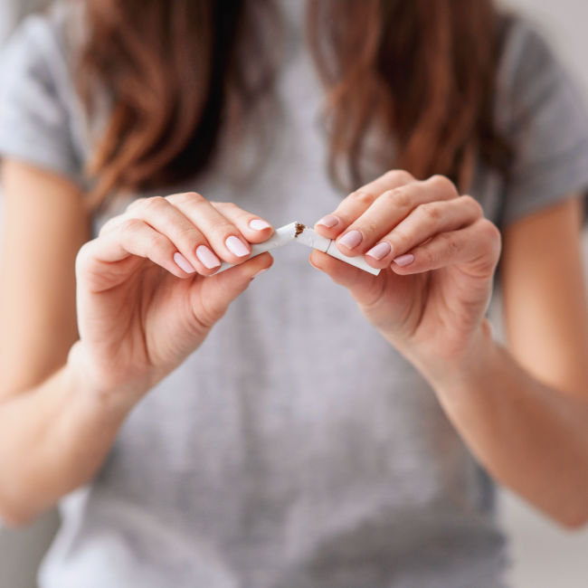 woman breaking cigarette in half