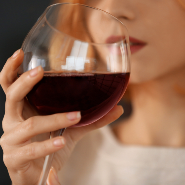 woman sipping on red wine large glass