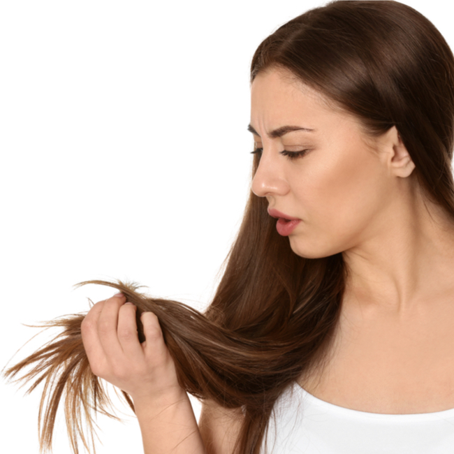 woman holding brown hair looking at split ends long locks white shirt