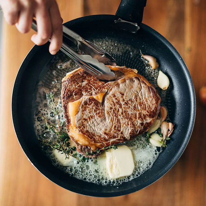 "Cooking a steak with butter, herbs, and garlic"