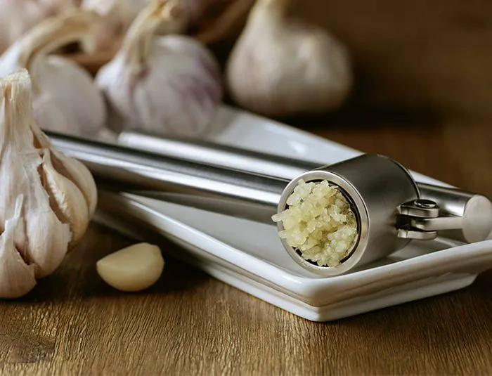 Garlic press with bulbs of garlic