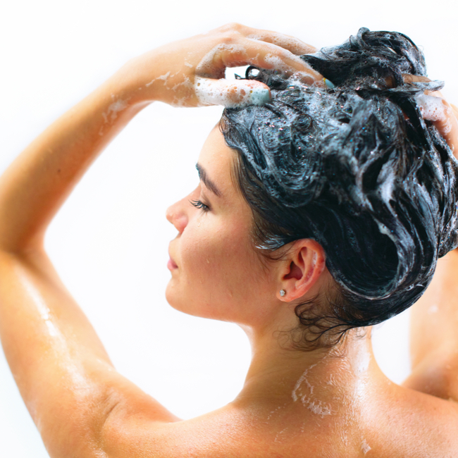 woman scrubbing her hair with shampoo in the shower blue liquid black hair