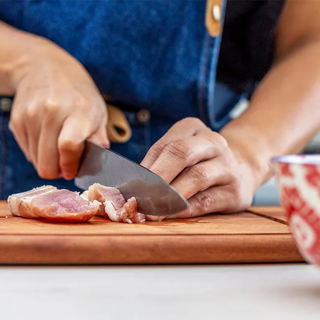 Chef chopping meat in a modern kitchen setting.