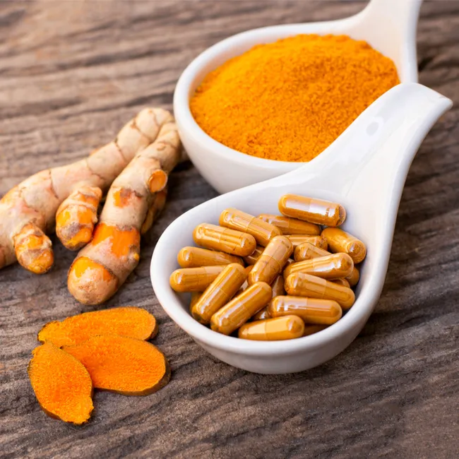 Curcumin supplement bottle with turmeric roots background.