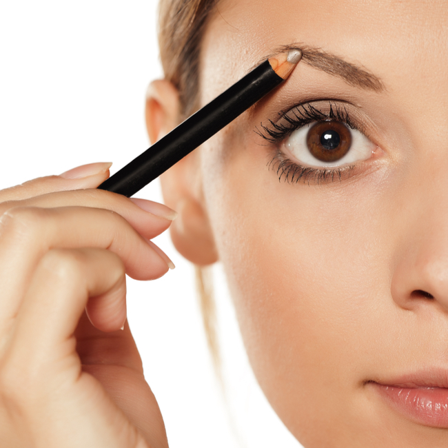 woman filling in eyebrows with pencil close-up