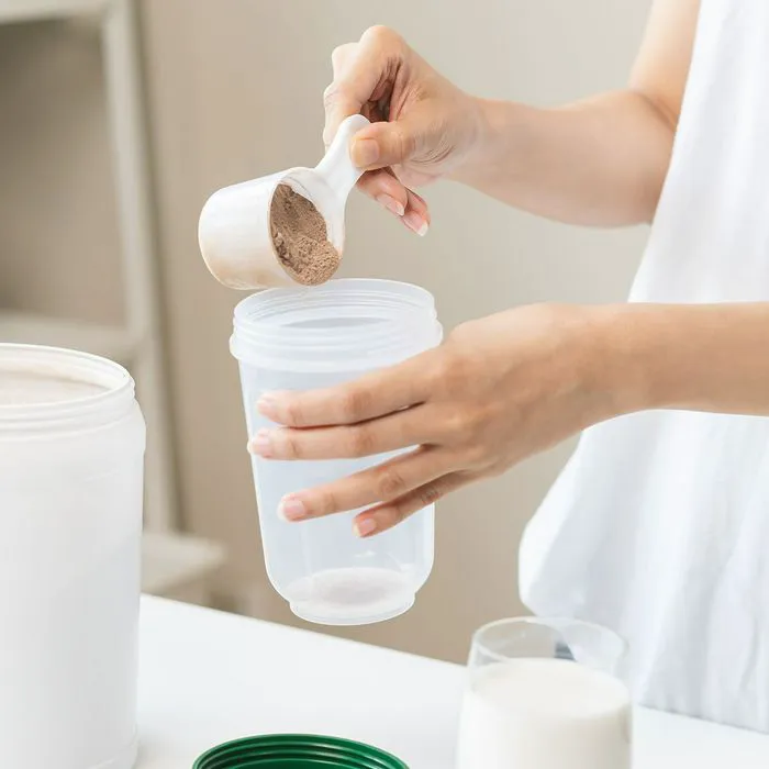 Woman preparing a healthy protein shake in kitchen