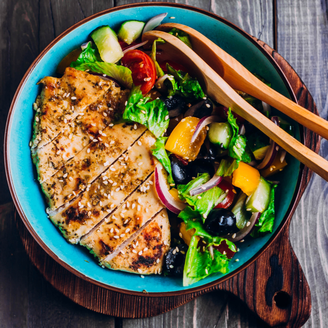 grilled chicken and mediterranean salad in salad bowl