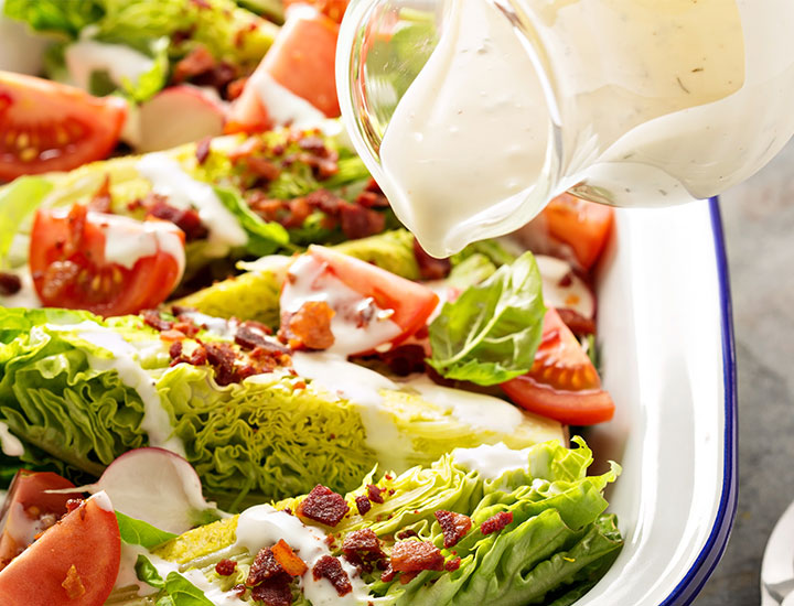 Pouring ranch dressing on wedge salad