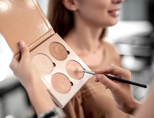 makeup artist holding brush to shimmery contour