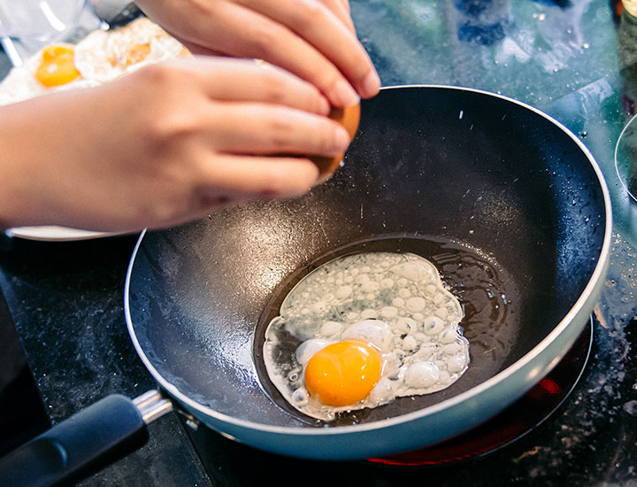 Woman cracking eggs into a frying pan