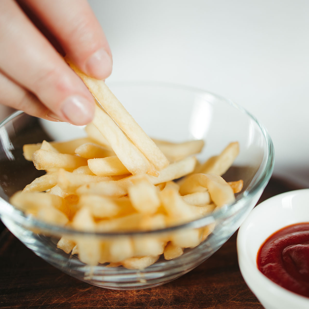 small bowl of french fries besides small bowl of ketchup