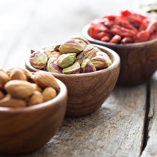 Colorful bowls of nuts, berries, and pistachios.