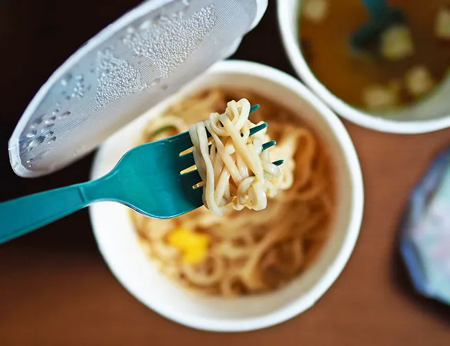 Bowl of steaming instant noodles with fresh toppings