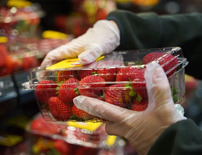 Walmart employee stocking fresh strawberries in grocery store.