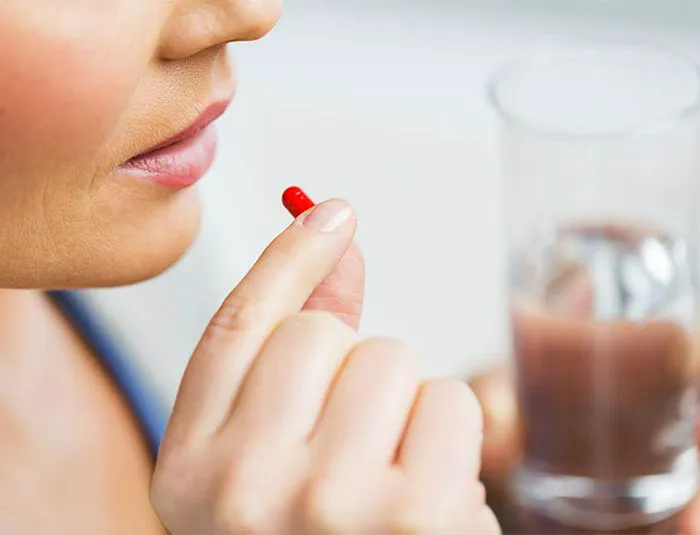 Woman taking a pill capsule with water