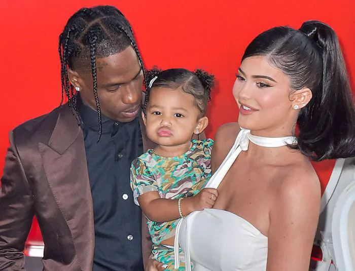 Kylie Jenner and Travis Scott with daughter Stormi at a public event.