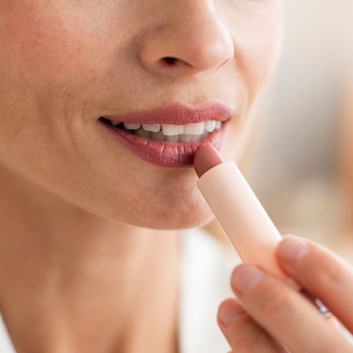 mature middle aged woman applying mauve lipstick