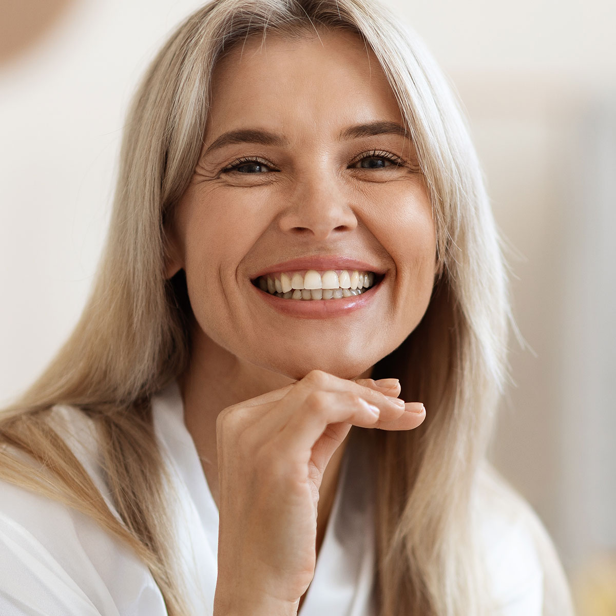 smiling mature woman wrinkles aging skin fine lines hand on chin