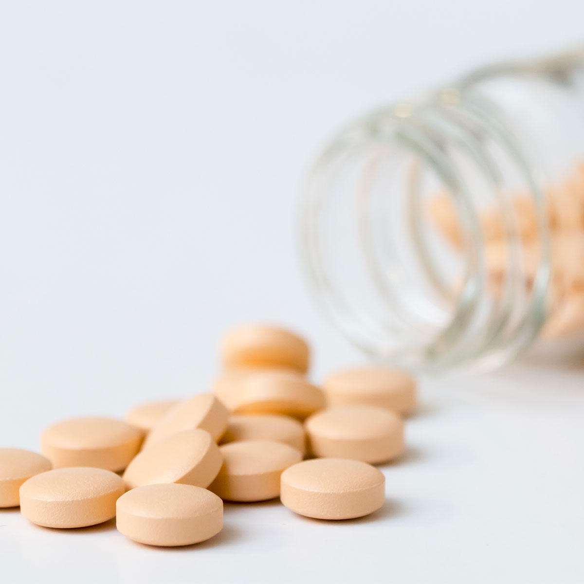 opened bottle of supplements from jar isolated white background