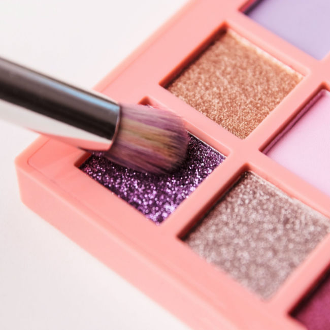 brush dipping into eyeshadow palette sparkly purple shade