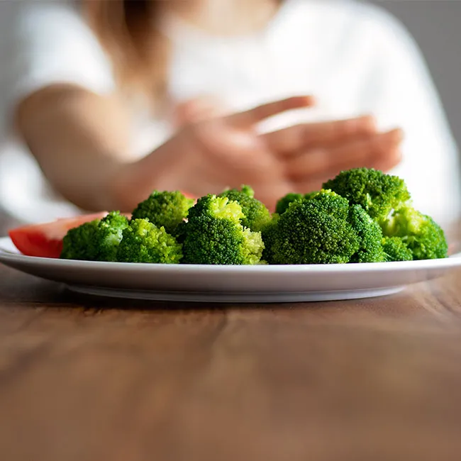 "Woman denying a meal with broccoli in front of her"