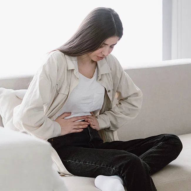 "Woman sitting on couch with stomach ache"