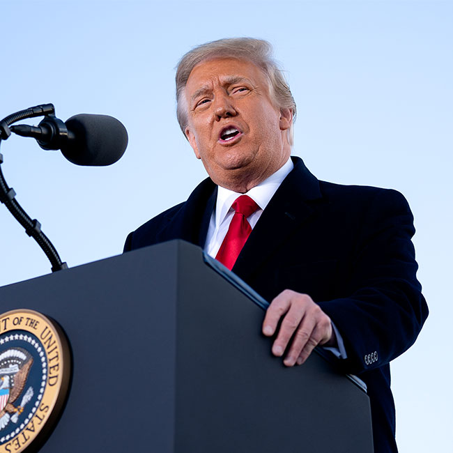 Donald Trump speaking podium red tie black suit blonde hair orange