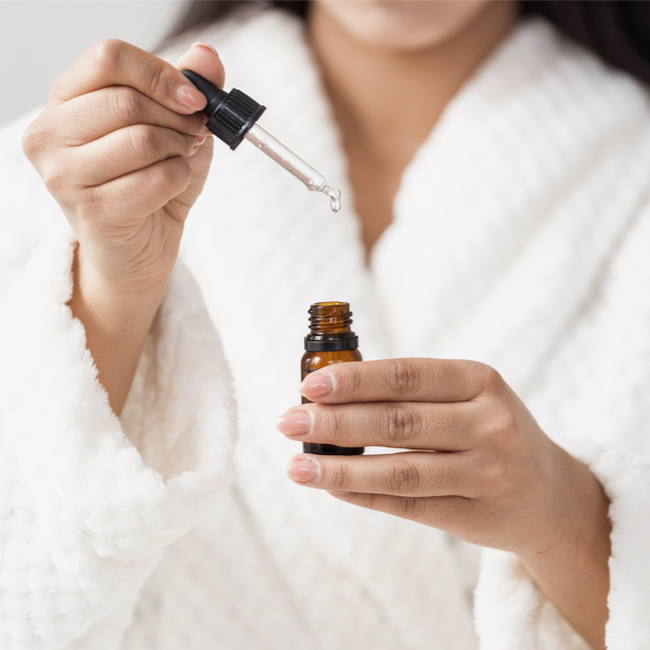 woman opening a bottle of serum droplet white robe holding product with hands