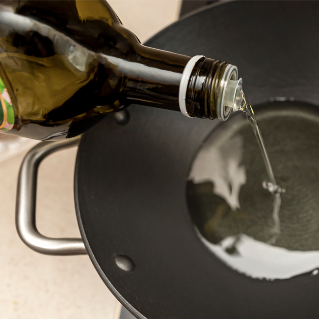 olive oil being poured from bottle into pan