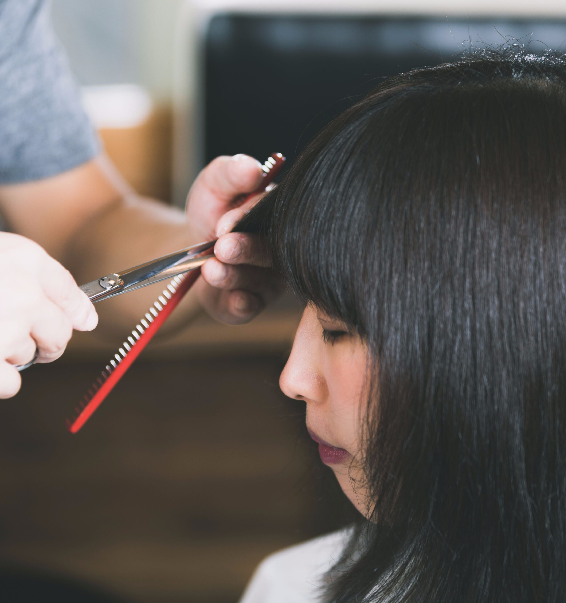 woman getting bang trim dark hair salon side angle profile