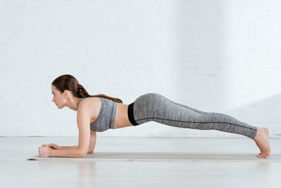 woman doing forearm plank in grey workout clothes