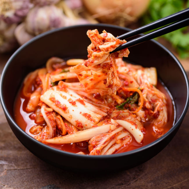 bowl of kimchi being eaten with chopsticks