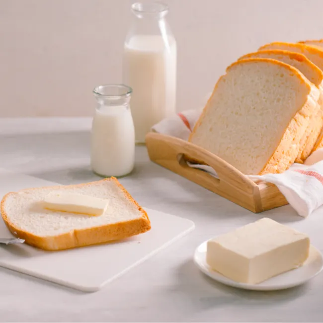 Freshly sliced bread with butter on a wooden board.