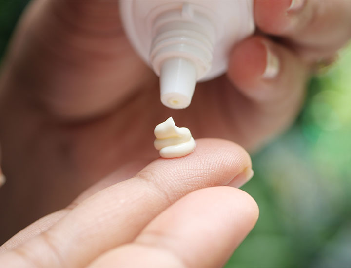 dollop of facial sunscreen on fingers from white tube