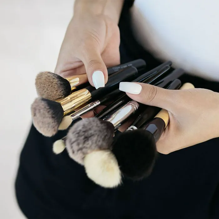 Makeup artist showcasing professional brushes ready for application.