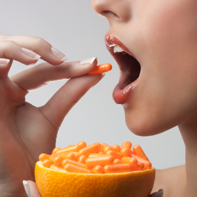 woman taking orange vitamin c supplement