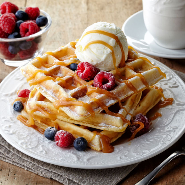 waffles topped with berries, syrup, and butter
