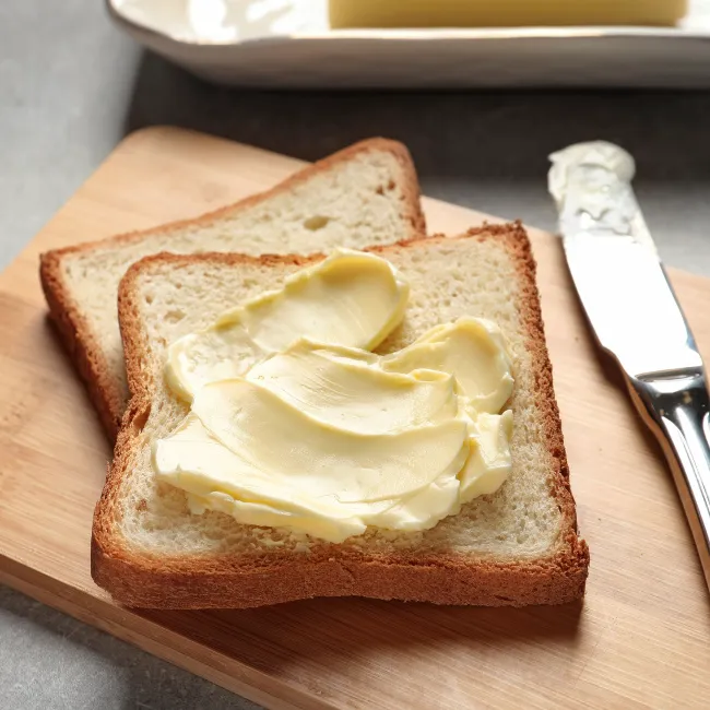 Slices of white bread with butter spread on top.