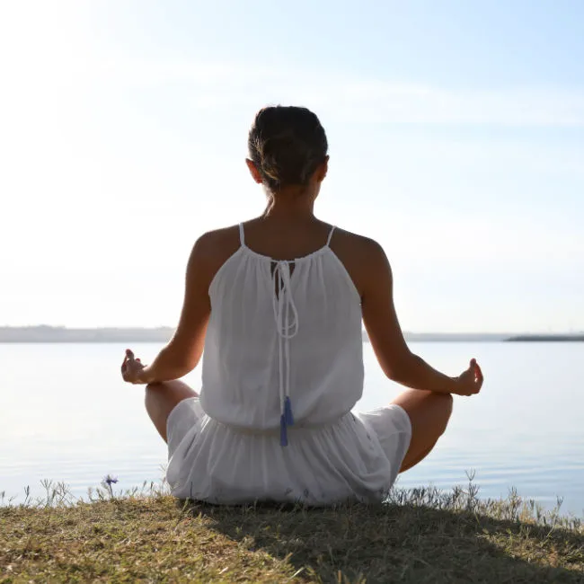woman meditating by the water