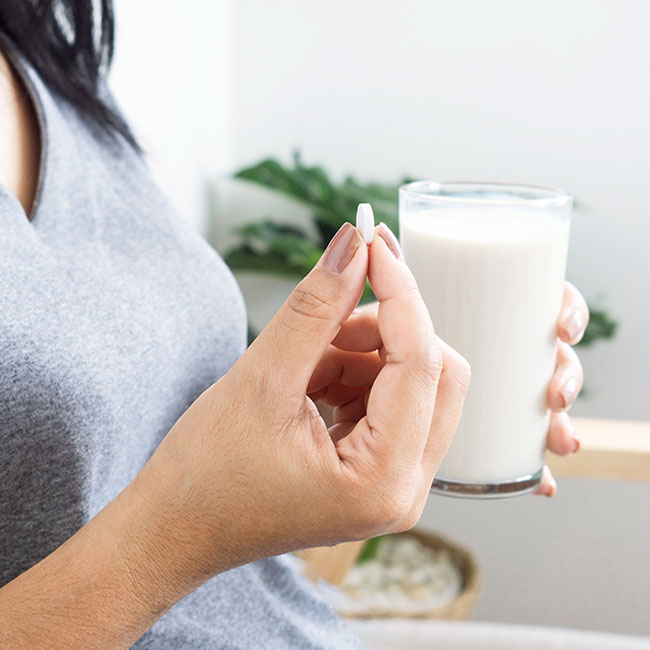 woman holding vitamin and glass of milk