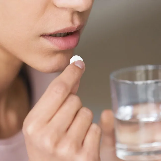 Woman taking a white supplement pill for health.