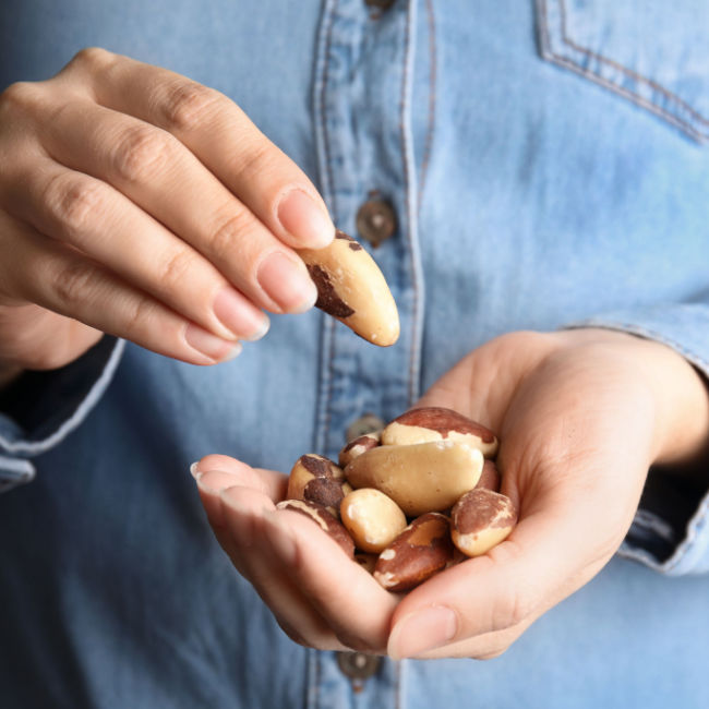 person eating handful of brazil nuts