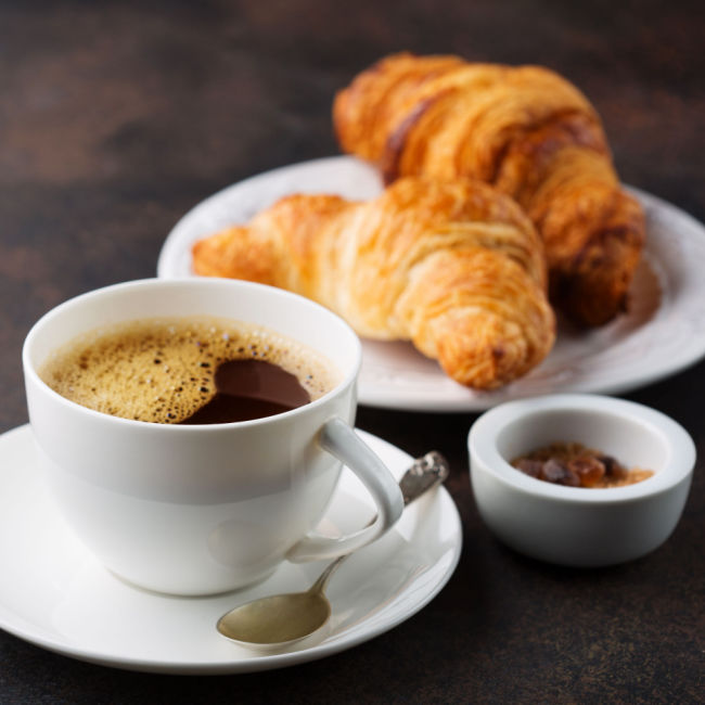 cup of coffee beside croissants