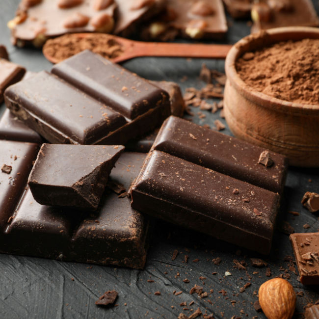 squares of dark chocolate next to small bowl of cocoa