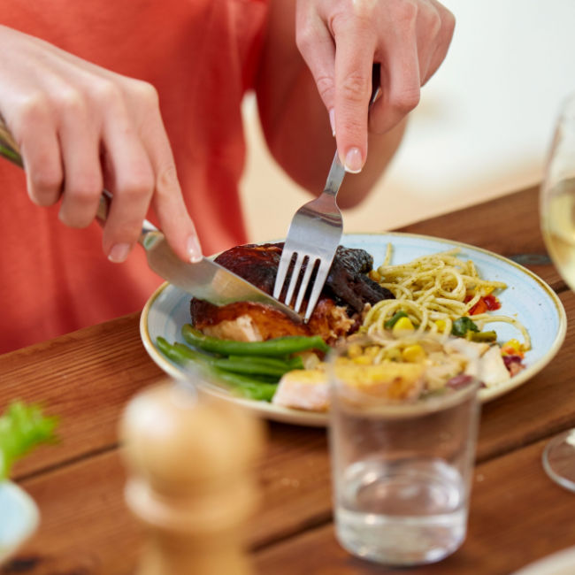 woman cutting into meat on dinner plate