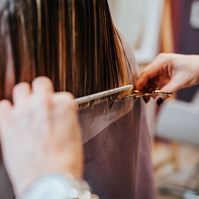 woman getting hair cut brown hair salon scissors